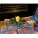 A Christmas Yule log candle centerpiece with a white candle in the middle. It decorates a fireplace hearth for the holidays. 